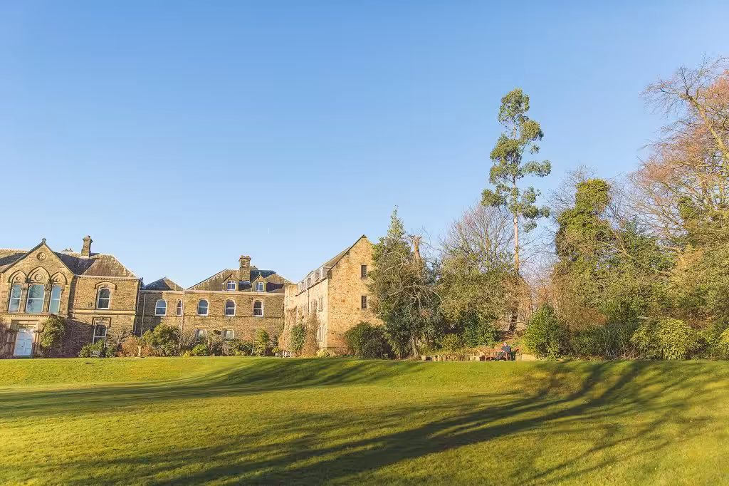 A wide, grassy expanse with some old stone buildings at the top
