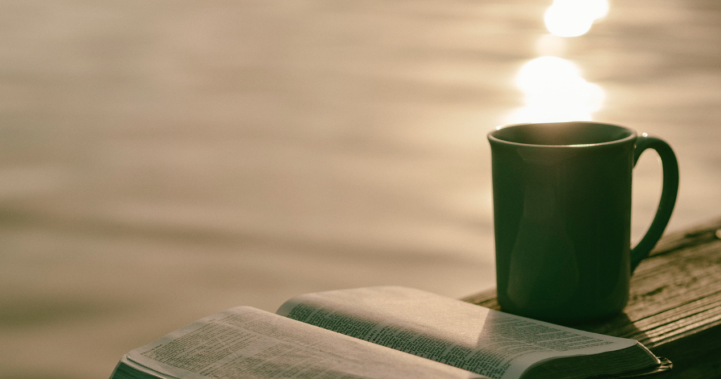 Reading bible with coffee by sea